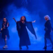 Zdjęcie z przedstawienia "Heksy z hołdy" przedstawiające trzy czarownice na tle mgły