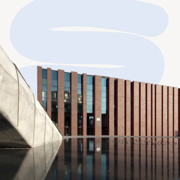 "Nowoczesny budynek z czerwonej cegły z pionowymi przeszklonymi pasami, będący siedzibą Narodowej Orkiestry Symfonicznej Polskiego Radia (NOSPR) w Katowicach. Na pierwszym planie widoczny jest fragment betonowej konstrukcji