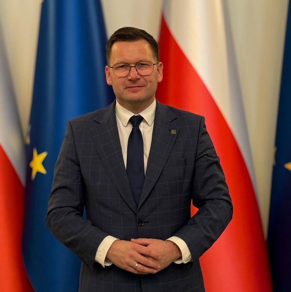 Szymon Michałek na tle flag