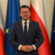 Szymon Michałek na tle flag
