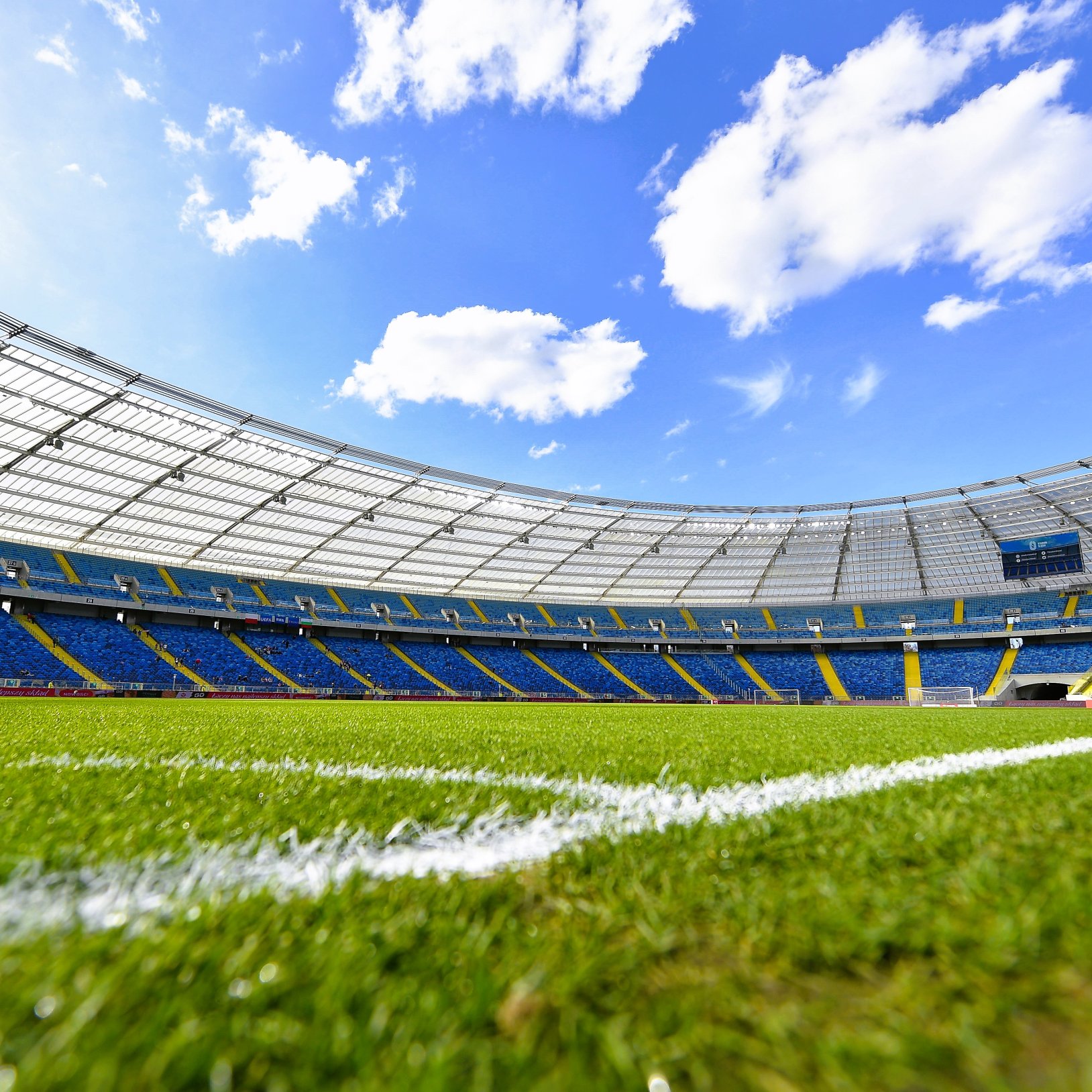 Wnętrze wystawy sportowej z kolorową instalacją poświęconą lekkoatletyce. Na pierwszym planie żółta figura sportowca w pozycji rzutu młotem, obok podświetlona gablota z rowerem oraz plansza z grafiką stadionu i napisem „Silesia Kamila Skolimowska Memorial