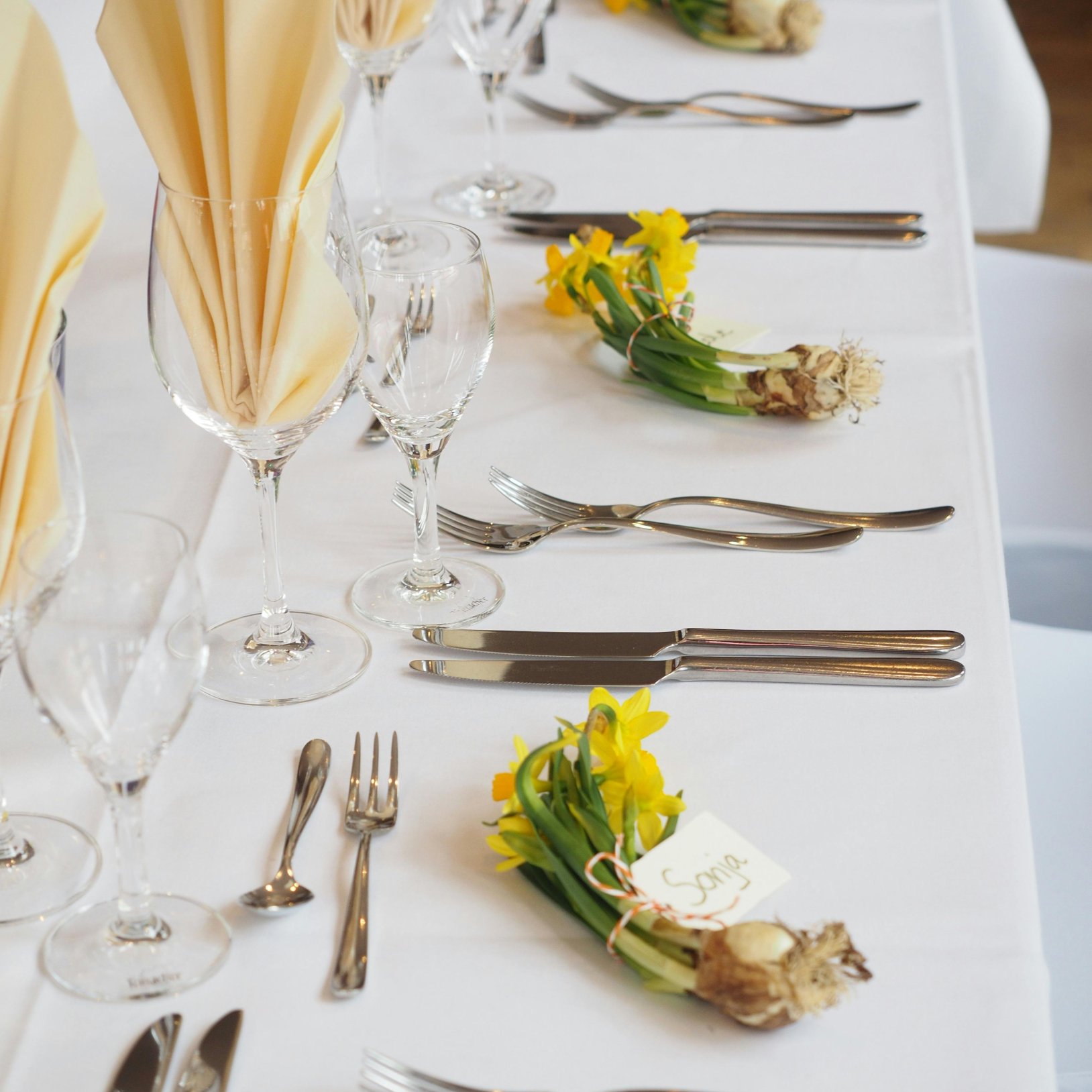 stół z białym obrusem oraz zastawą z zielonymi i żółtymi dekoracjami