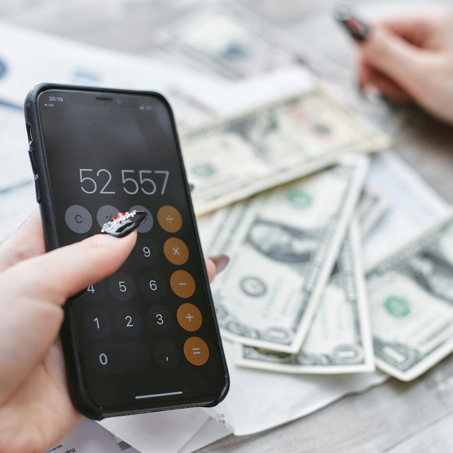 zdjęcie kalkulatora, pieniędzy i ręki trzymającej długopis