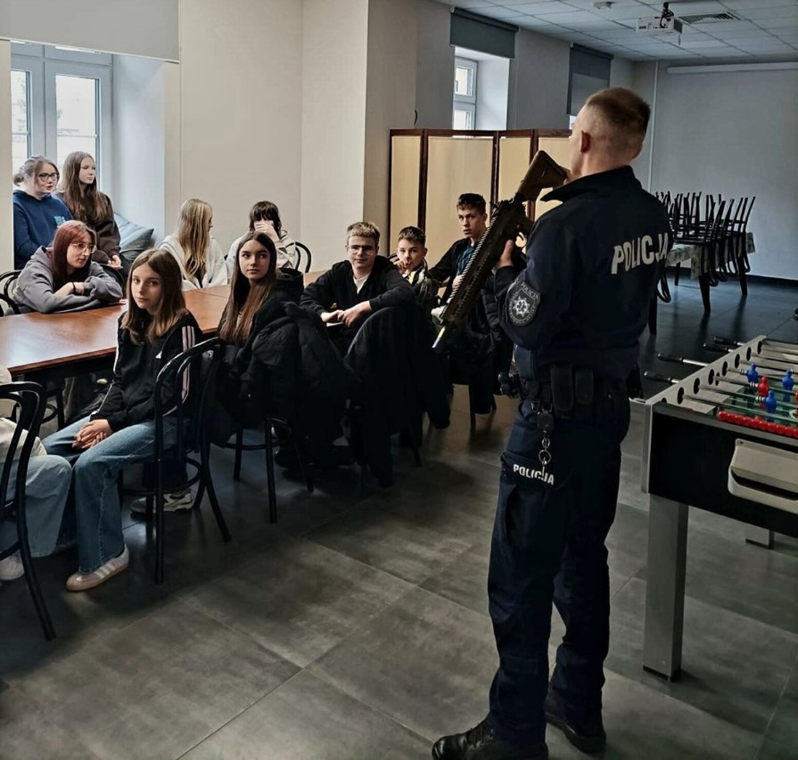 Młodzież słuchająca policjanta z bronią