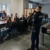 Młodzież słuchająca policjanta z bronią