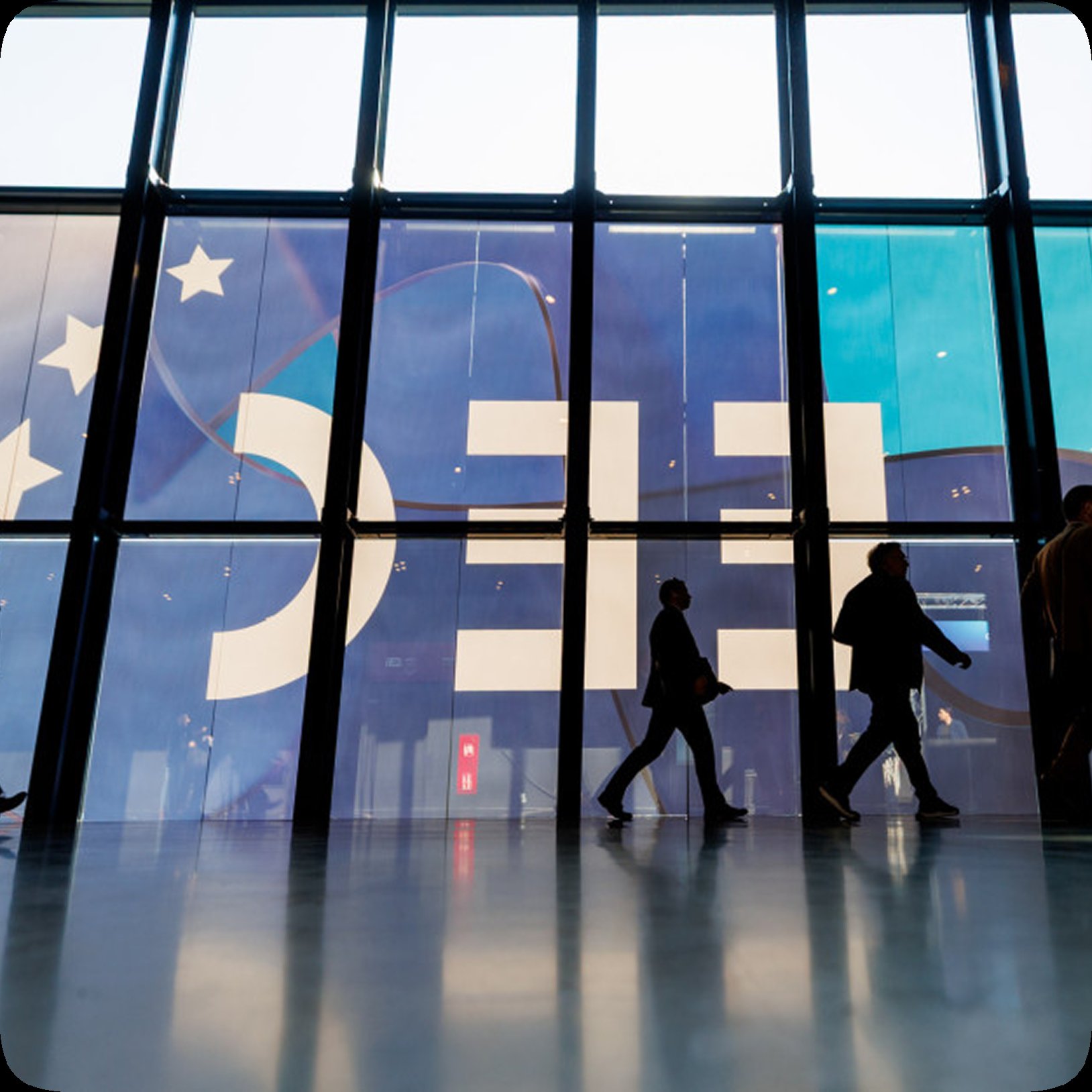 Zdjęcie osób przechodzących przed banerem EEC