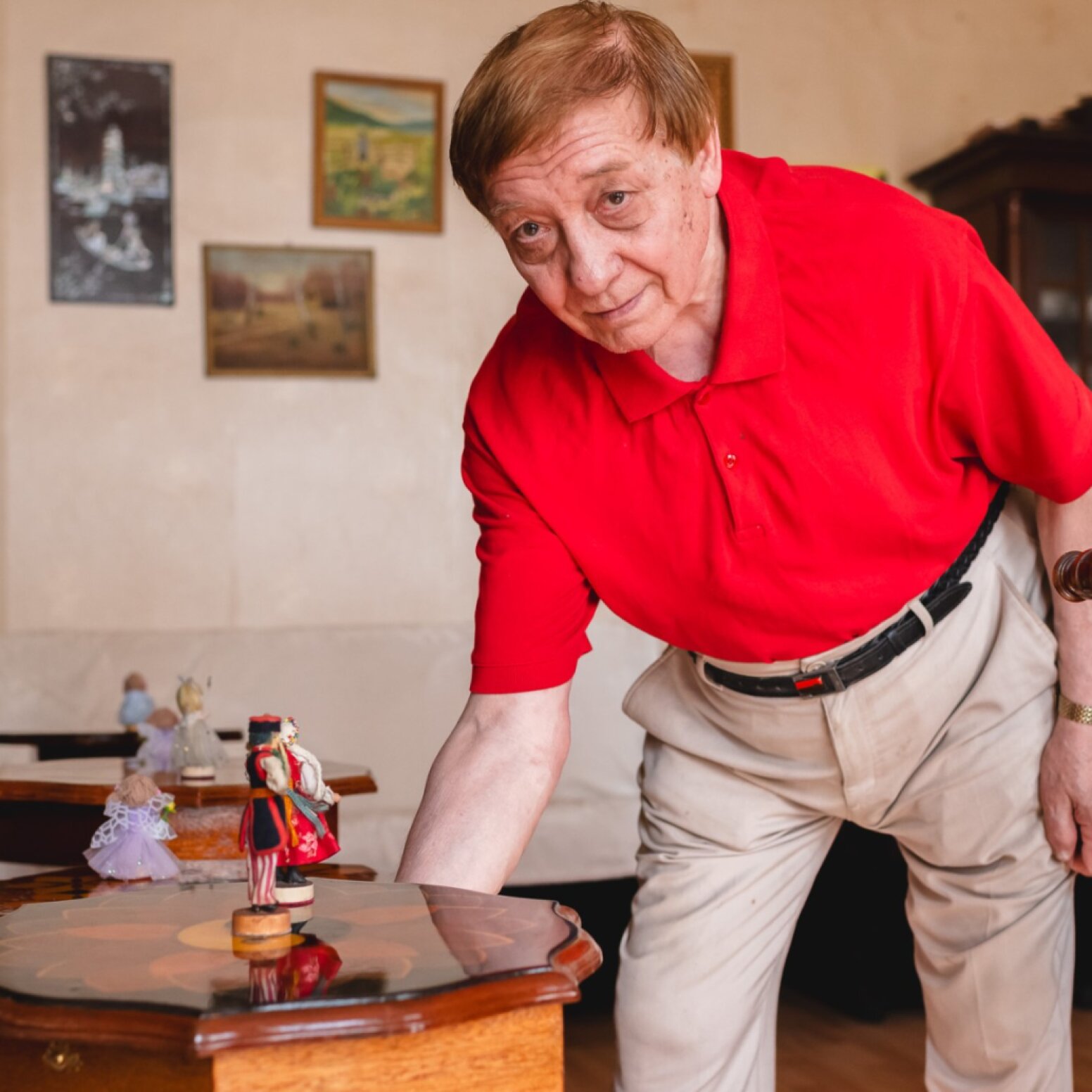 Stolarz pochylający się nad stolikiem kawowym z figurkami Krakowianek