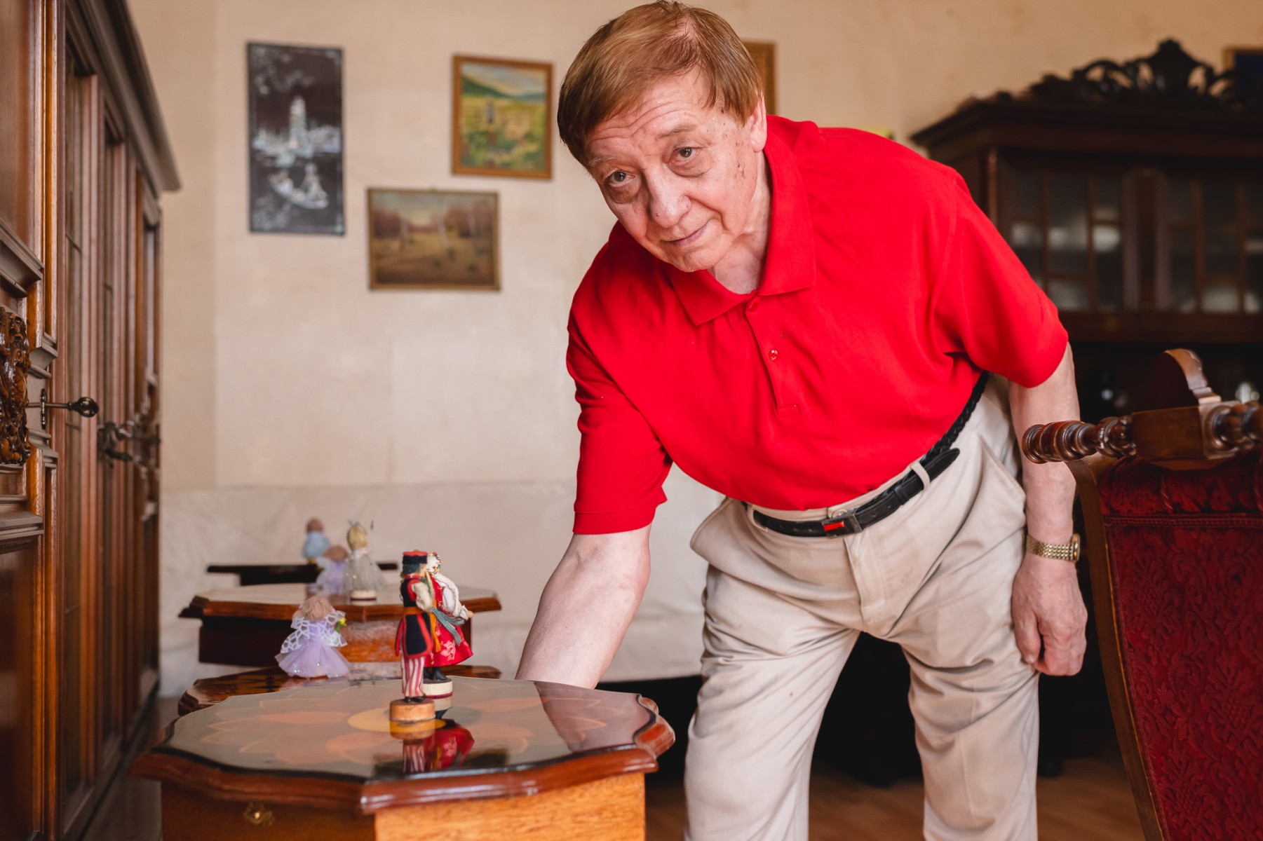 Stolarz pochylający się nad stolikiem kawowym z figurkami Krakowianek